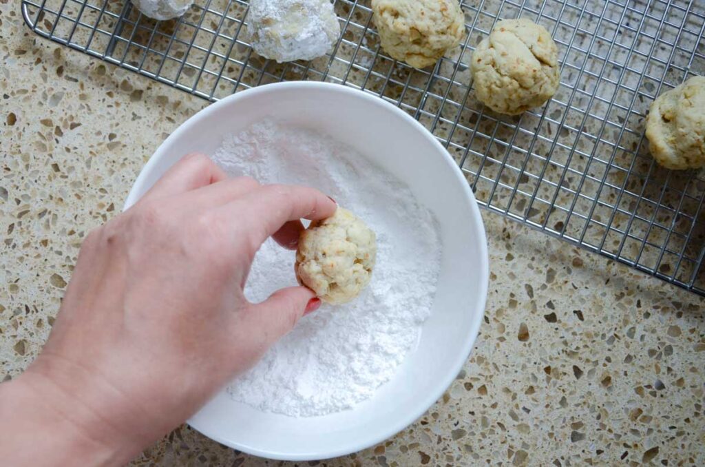 rolling sourdough Russian tea cookies in powdered sugar