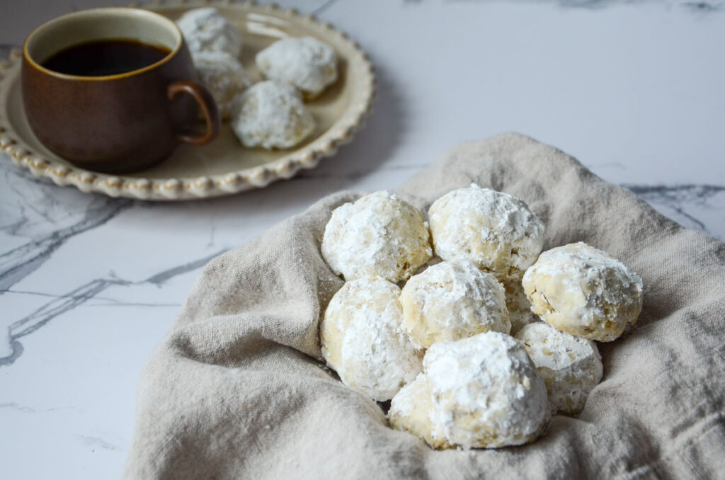 cookies on a lined basket with a plate of cookies and a cup of coffee