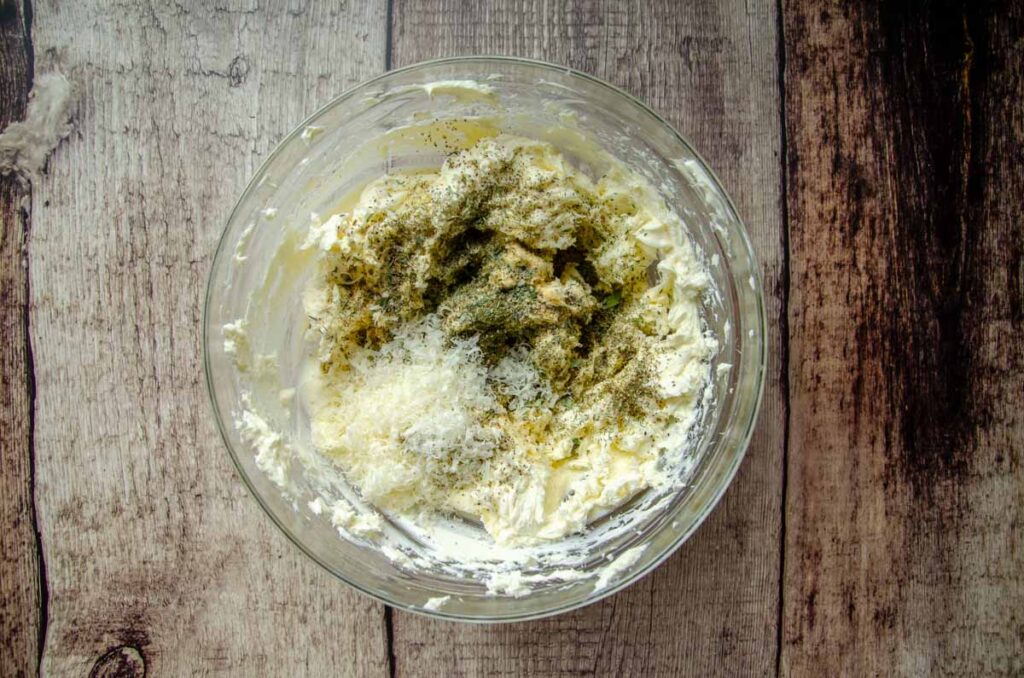 adding seasoning to cream cheese for homemade cheese dip