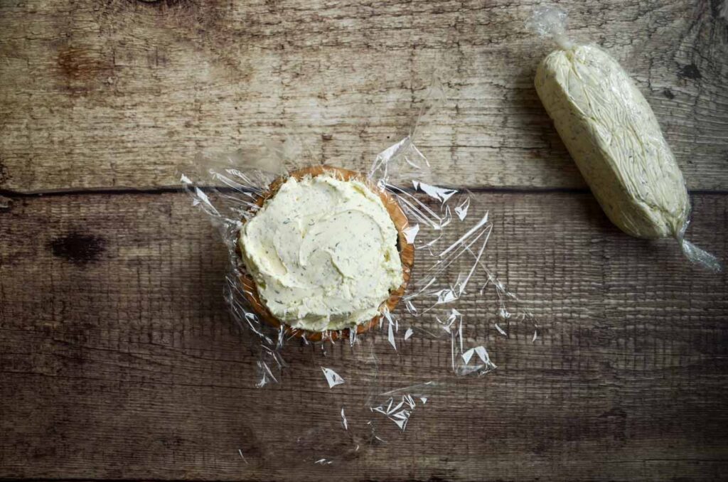 Boursin cheese dip in plastic wrap lined bowl and second rolled into a cheese log. 