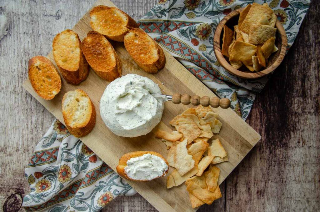 Boursin cheese on wooden platter with crackers and bread