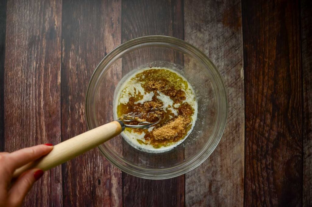 butter and brown sugar in glass bowl mixing with a danish dough whisk