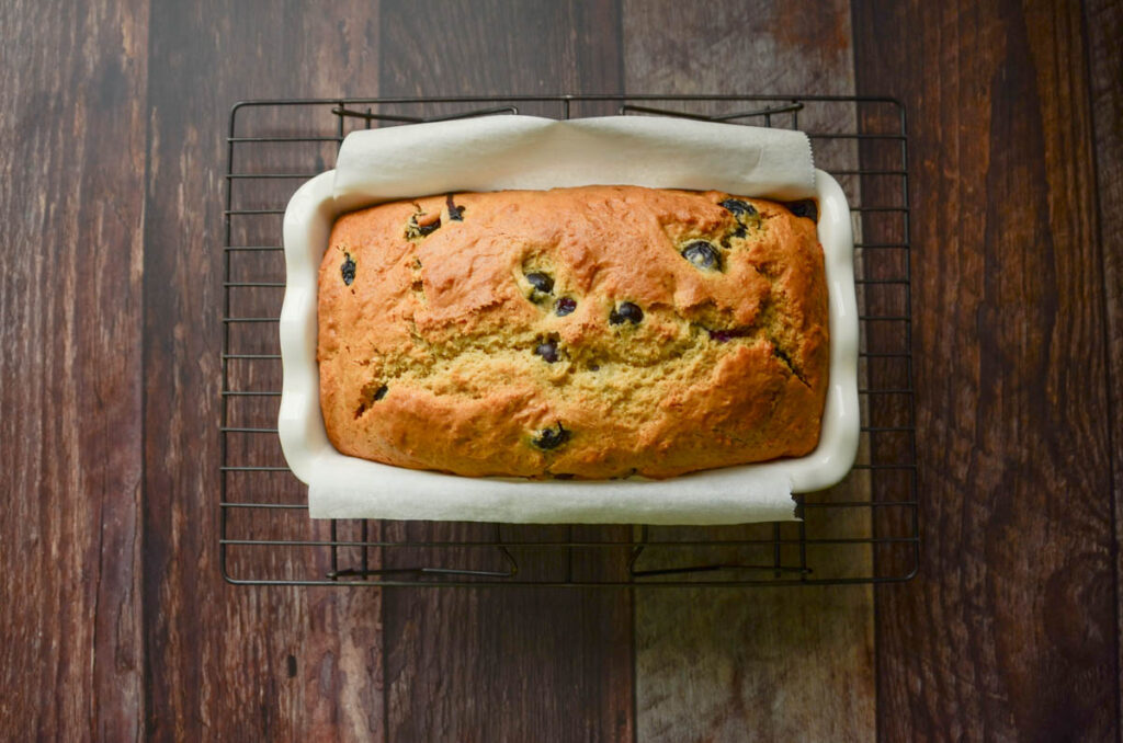 baked blueberry bread in a parchment lined loaf pan