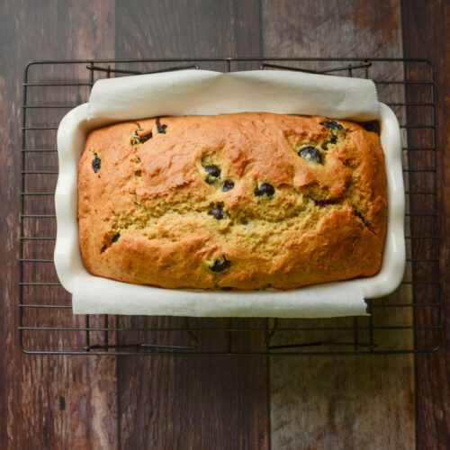 baked blueberry bread in a parchment lined loaf pan