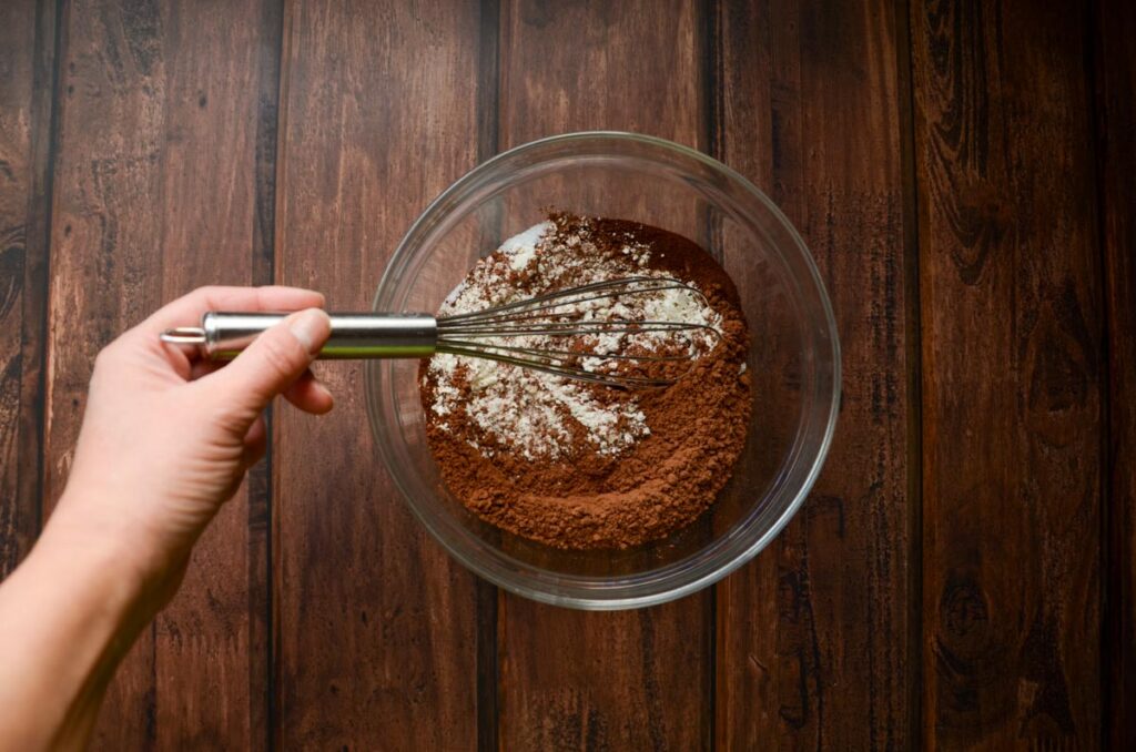 Whisking dry ingredients for double chocolate sourdough cookies in a glass bowl.