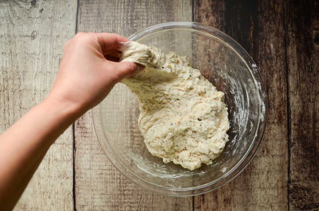 stretching  sourdough everything bread in glass bowl