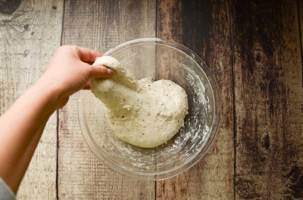 stretching sourdough everything bread in a glass bowl