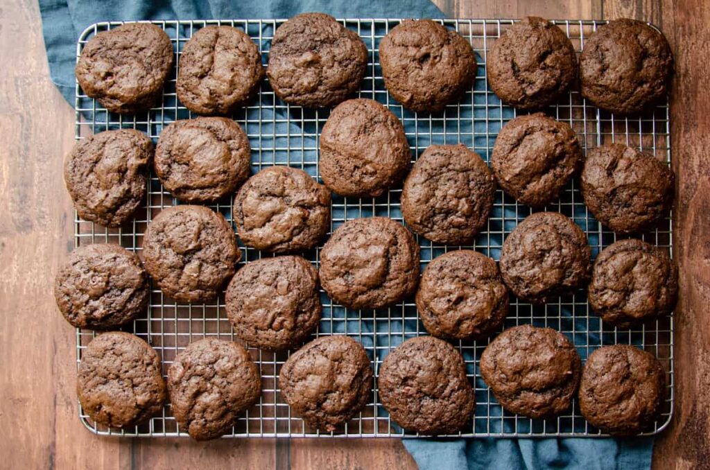 double chocolate sourdough cookies on a wire rack with a blue napkin underneath. 