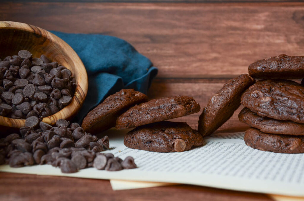 stacks of sourdough double chocolate chip cookies with a bowl of chocolate chips