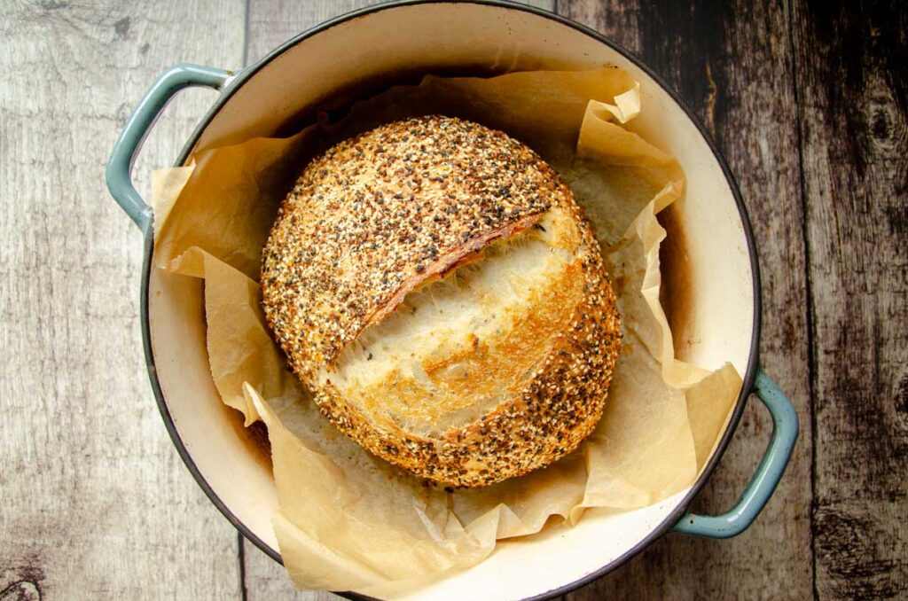 Sourdough everything bread on parchment paper in Dutch oven