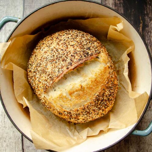 Sourdough everything bread on parchment paper in Dutch oven