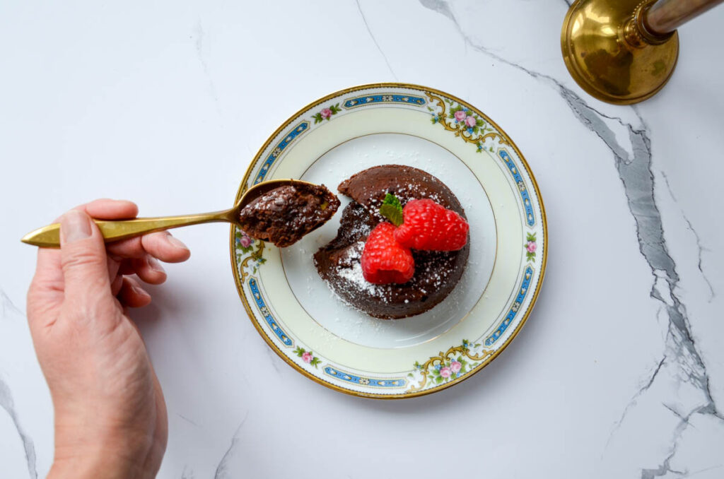 chocolate molten lava cake on a plate with a bite on a gold spoon