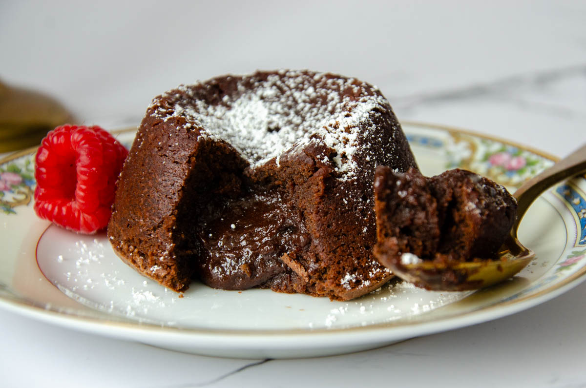 molten lava cake on a plate with a spoon and raspberry