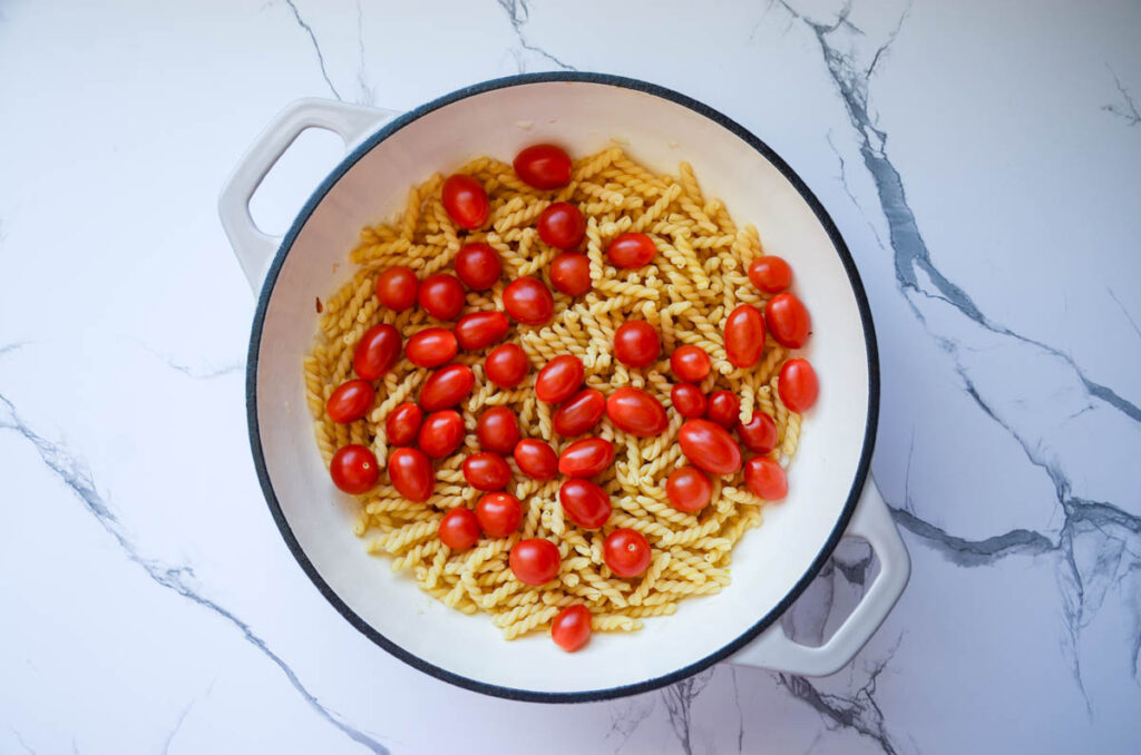 tomatoes, pasta, and onions in enameled cast iron.