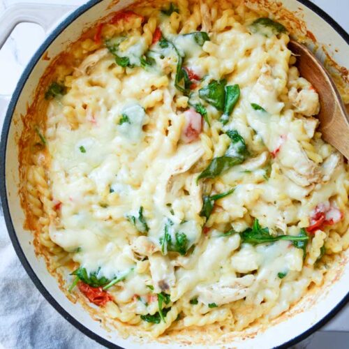 Boursin chicken bake in a large enameled iron skillet with a wooden spoon.