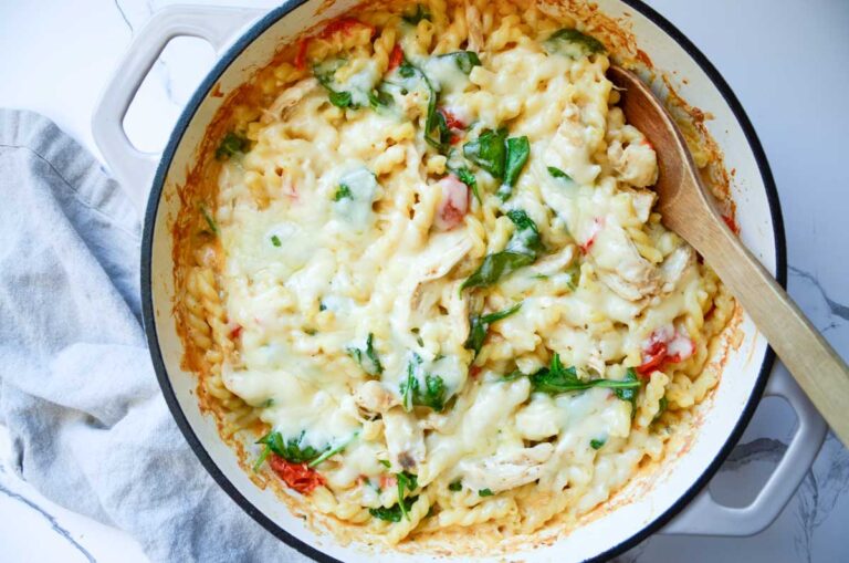 Boursin chicken bake in a large enameled iron skillet with a wooden spoon.