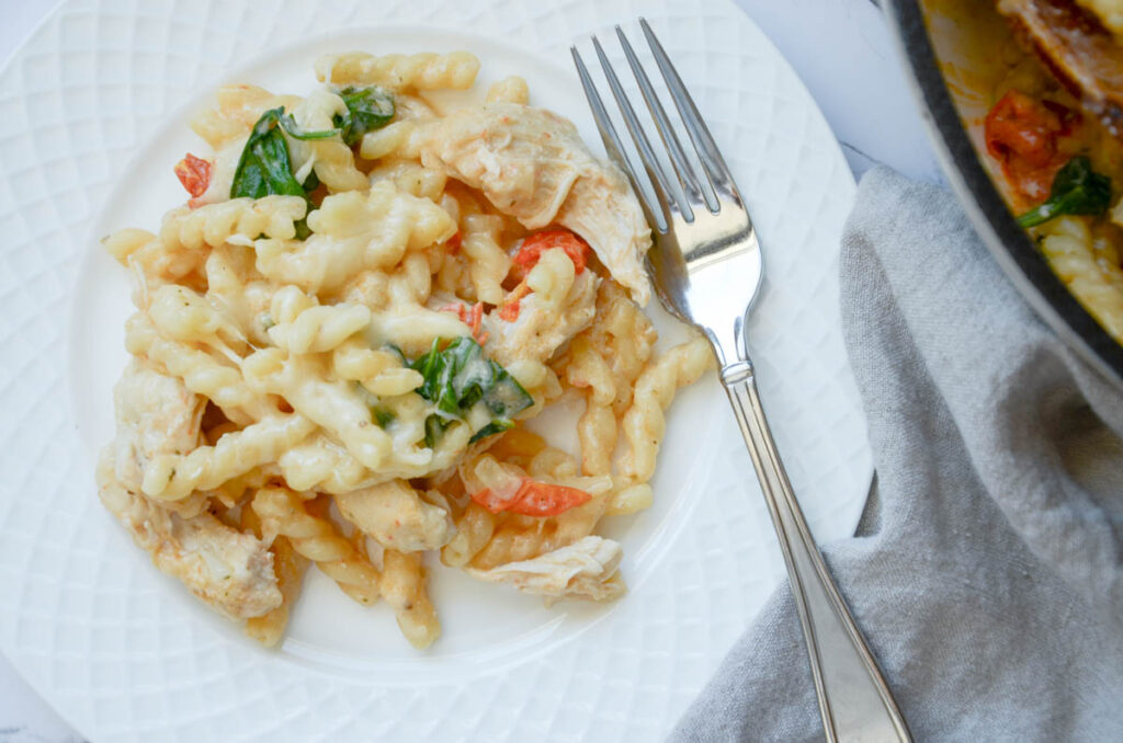 Boursin pasta chicken bake on a white plate with a fork and napkin