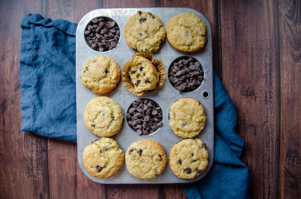 sourdough chocolate chip muffins in a muffin tin with chocolate chips in a few cups