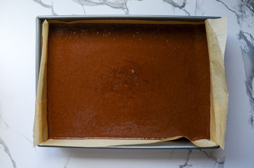 cake batter in a parchment lined baking pan