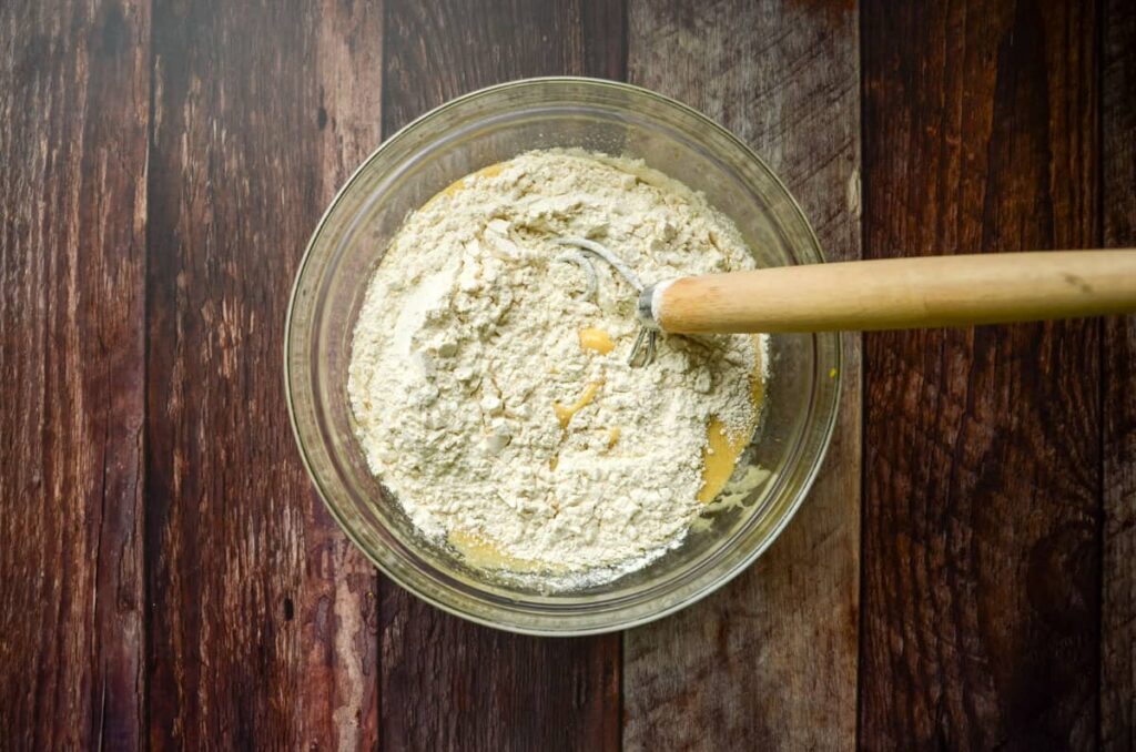 adding dry ingredients to wet ingredients in a glass bowl