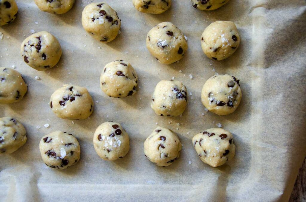 chocolate chip cookie dough bites on a parchment paper lined baking pan