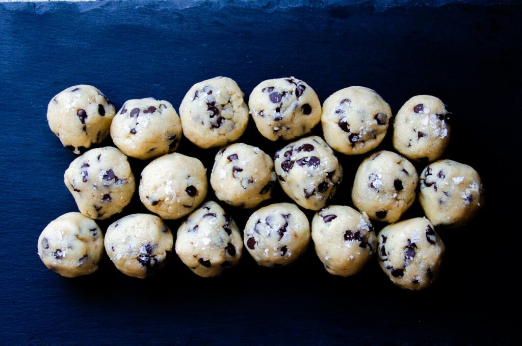 chocolate chip cookie dough bites balls on a black slate plate.