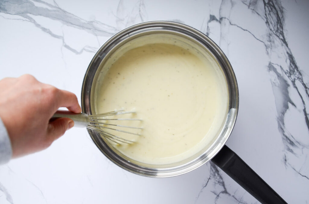 Whisking milk into bechamel in a sauce pan