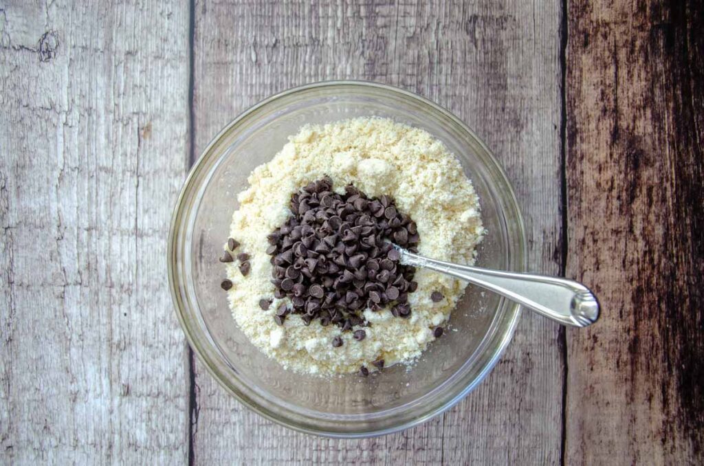 adding almond flour and chocolate chips in the glass bowl