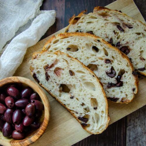 sourdough olive with parmesan, garlic, and rosemary bread slices and a bowl of olives.