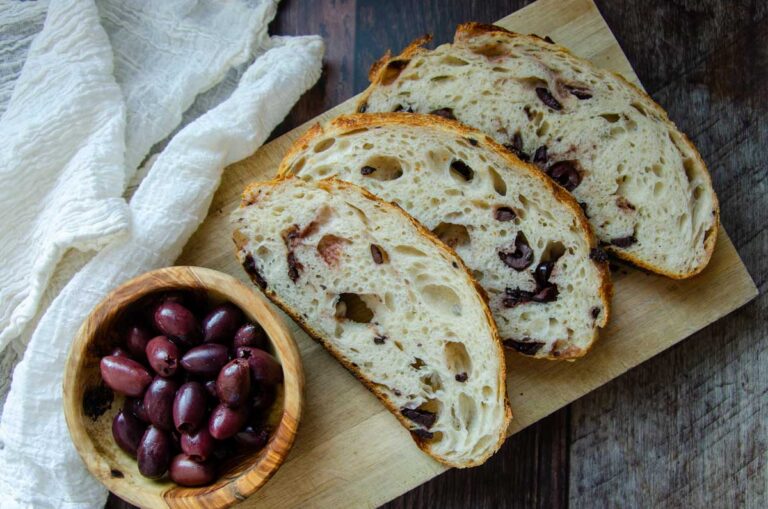 sourdough olive with parmesan, garlic, and rosemary bread slices and a bowl of olives.