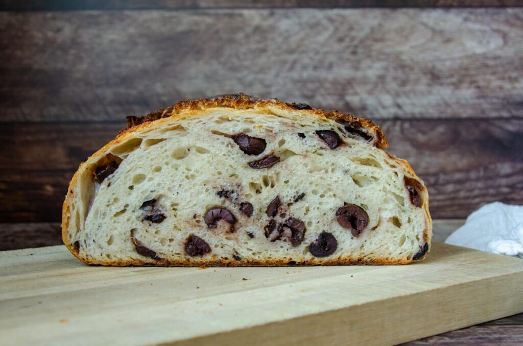 rosemary parmesan olive sourdough bread on a wood cutting board