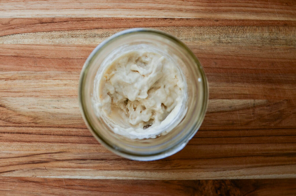 feeding a dehydrating sourdough starter in a glass jar. 