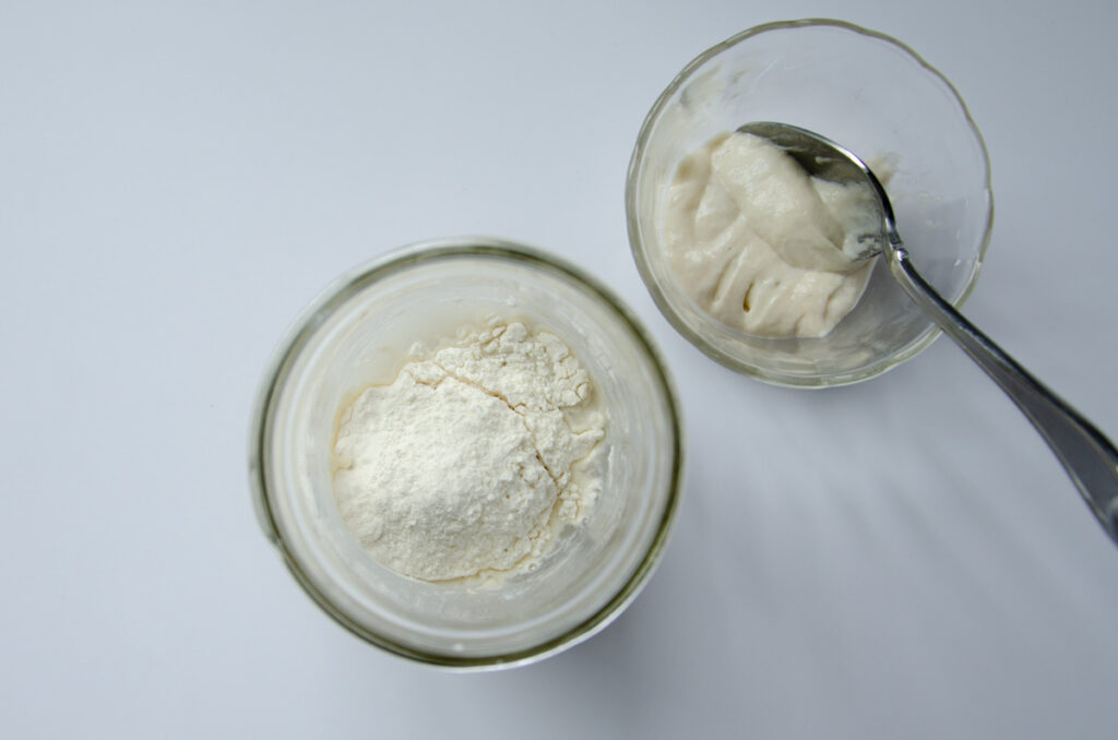 discarding some sourdough starter in a small dish. A jar is fed with water and flour