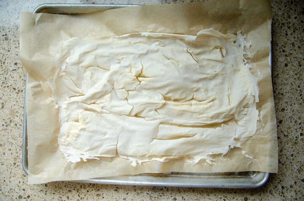 Dehydrated sourdough starter on a parchment paper lined baking sheet.