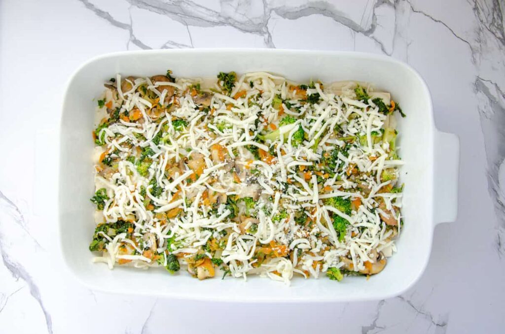 sprinkled shredded cheese over vegetable layer in baking dish