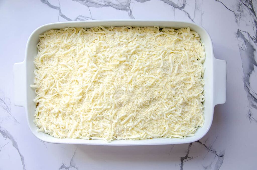 shredded cheese in baking dish for vegetable lasagna