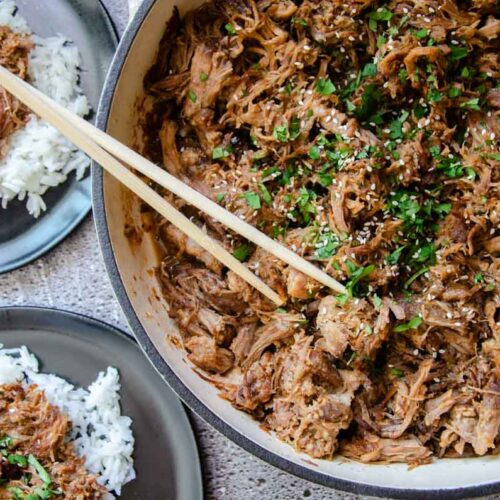 Korean pulled pork in a large skillet, and small plates next to it.