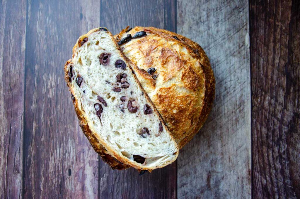 a loaf of rosemary parmesan olive sourdough bread loaf cut in half