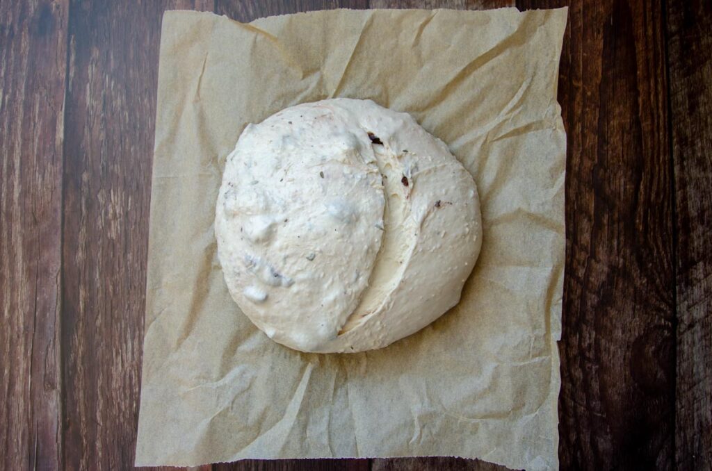 scored sourdough bread dough on a piece of parchment paper