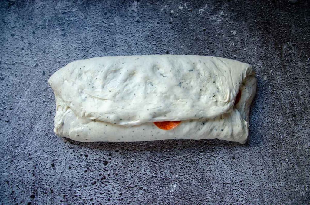 folding top half of sourdough pepperoni bread dough