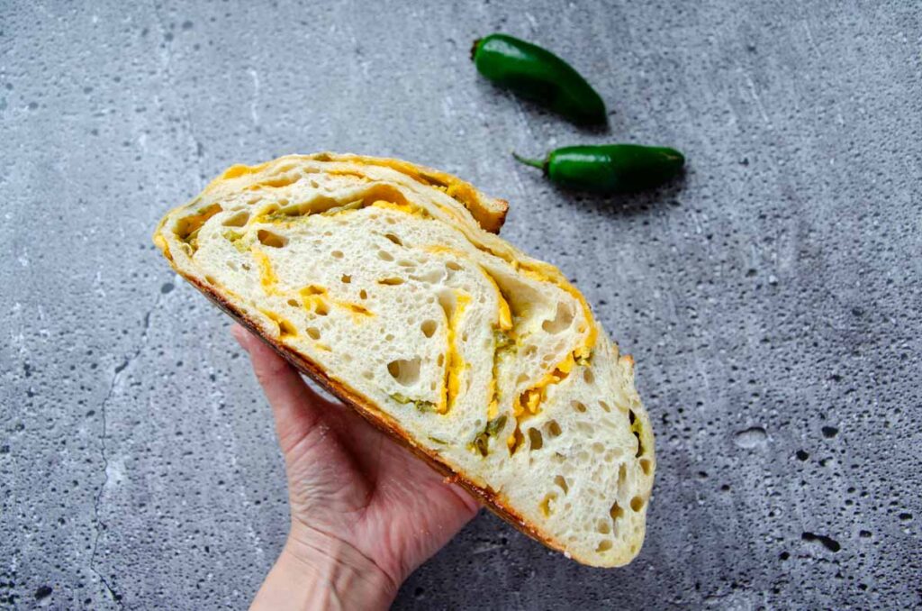 holding a cut loaf of sourdough jalapeno cheddar bread