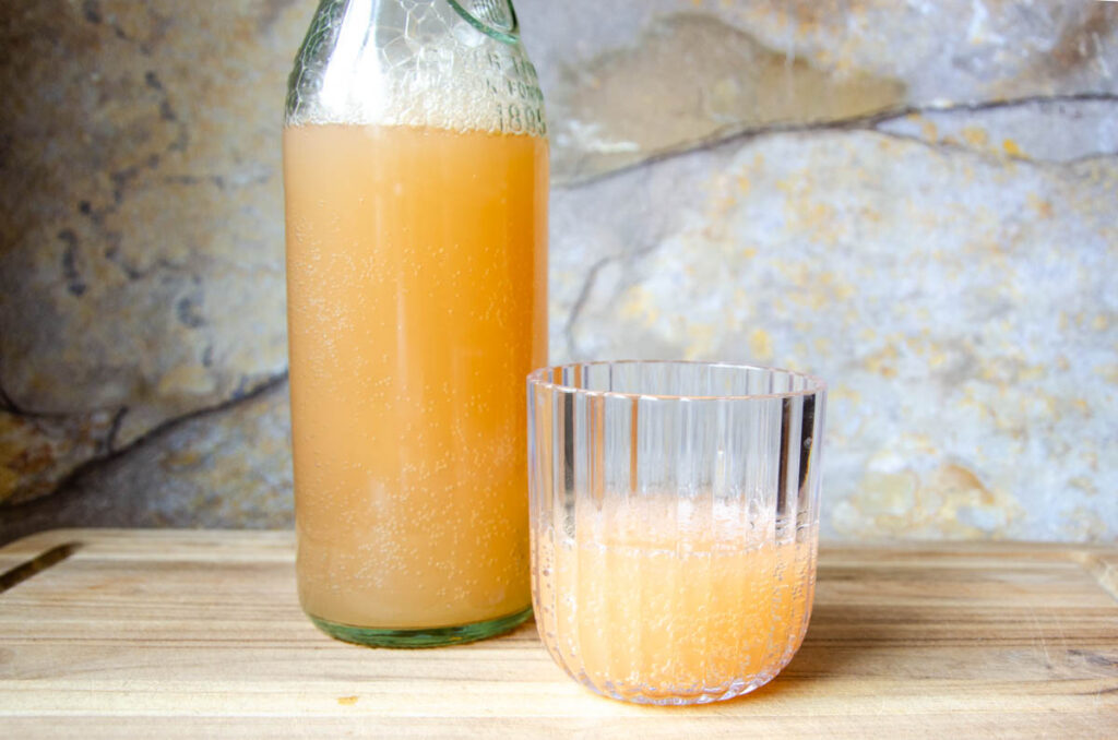 Ginger bug soda in a cup and glass bottle