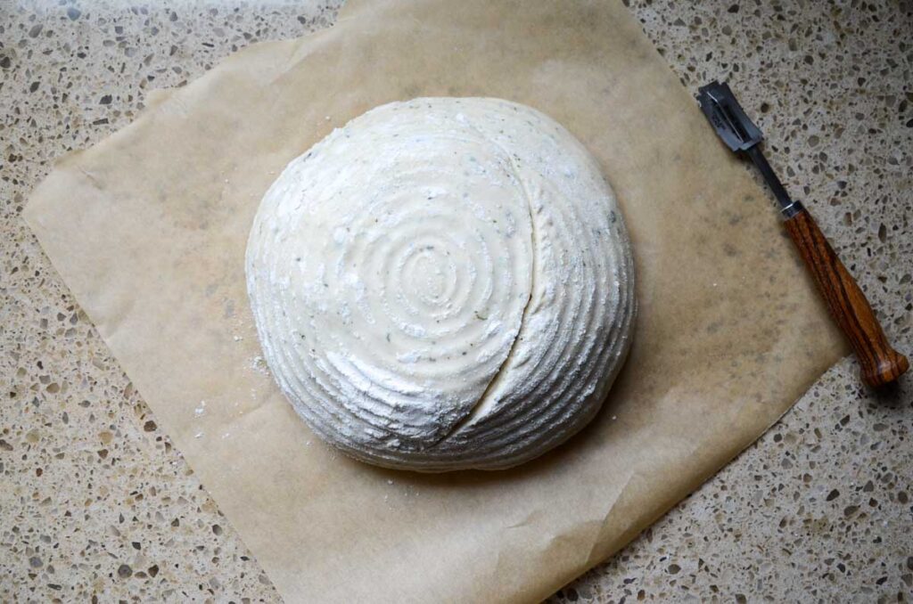 using a lame to score the top of the sourdough bread dough
