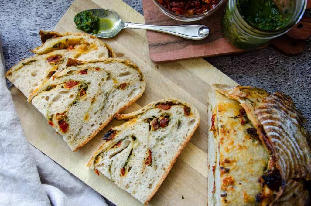 sourdough sun dried tomato pesto bread slices on a wooden board