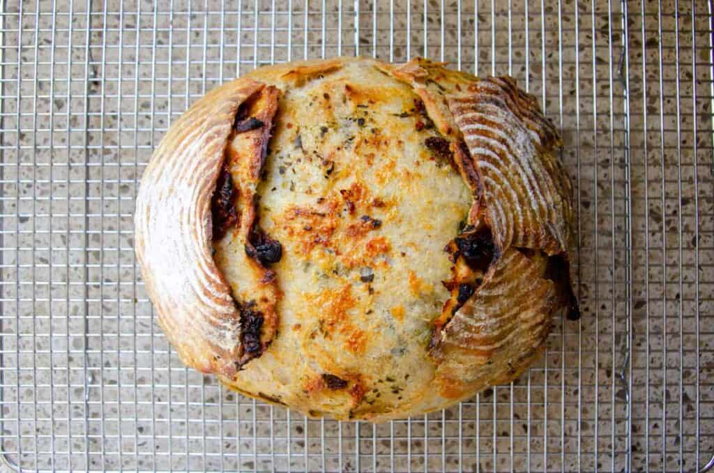 letting the sourdough pesto sun dried tomato bread cool on a wire rack