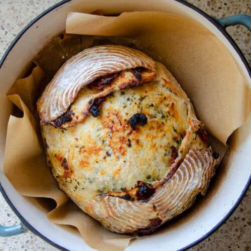 a loaf of sourdough sundried tomato pesto bread in a Dutch oven.