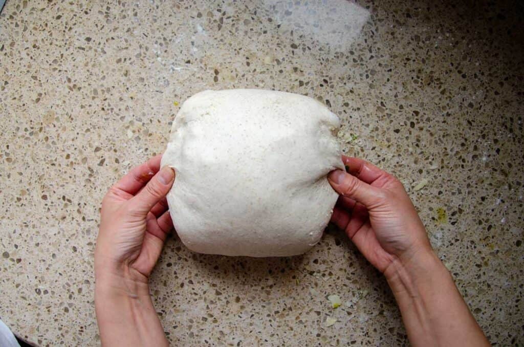 pinching the sides of the dough ball close