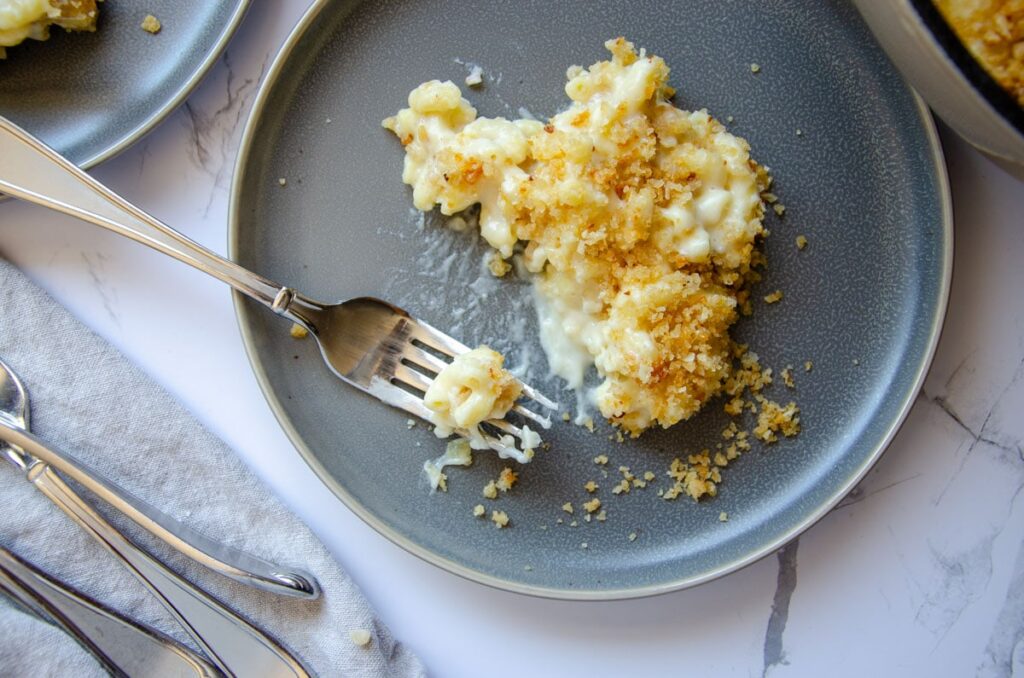 rdough mac and cheese with bread crumb topping on a plate with a fork
