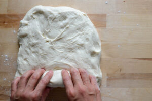 rolling out the sourdough sandwich bread dough into a log
