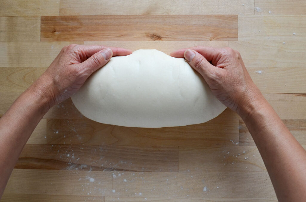 pulling the dough to create a bit of tension over the top of the dough